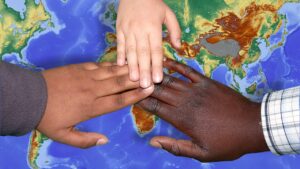 Migration, Kooperation, drei Hände auf Weltkarte
