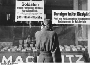 Warnung an Soldaten vor Fahnenflucht im Februar 1945 in Danzig, https://upload.wikimedia.org/wikipedia/commons/5/53/Bundesarchiv_Bild_146-1996-030-12A%2C_Danzig%2C_Frau_vor_Schaufenster.jpg / CC-BY-SA 3.0.